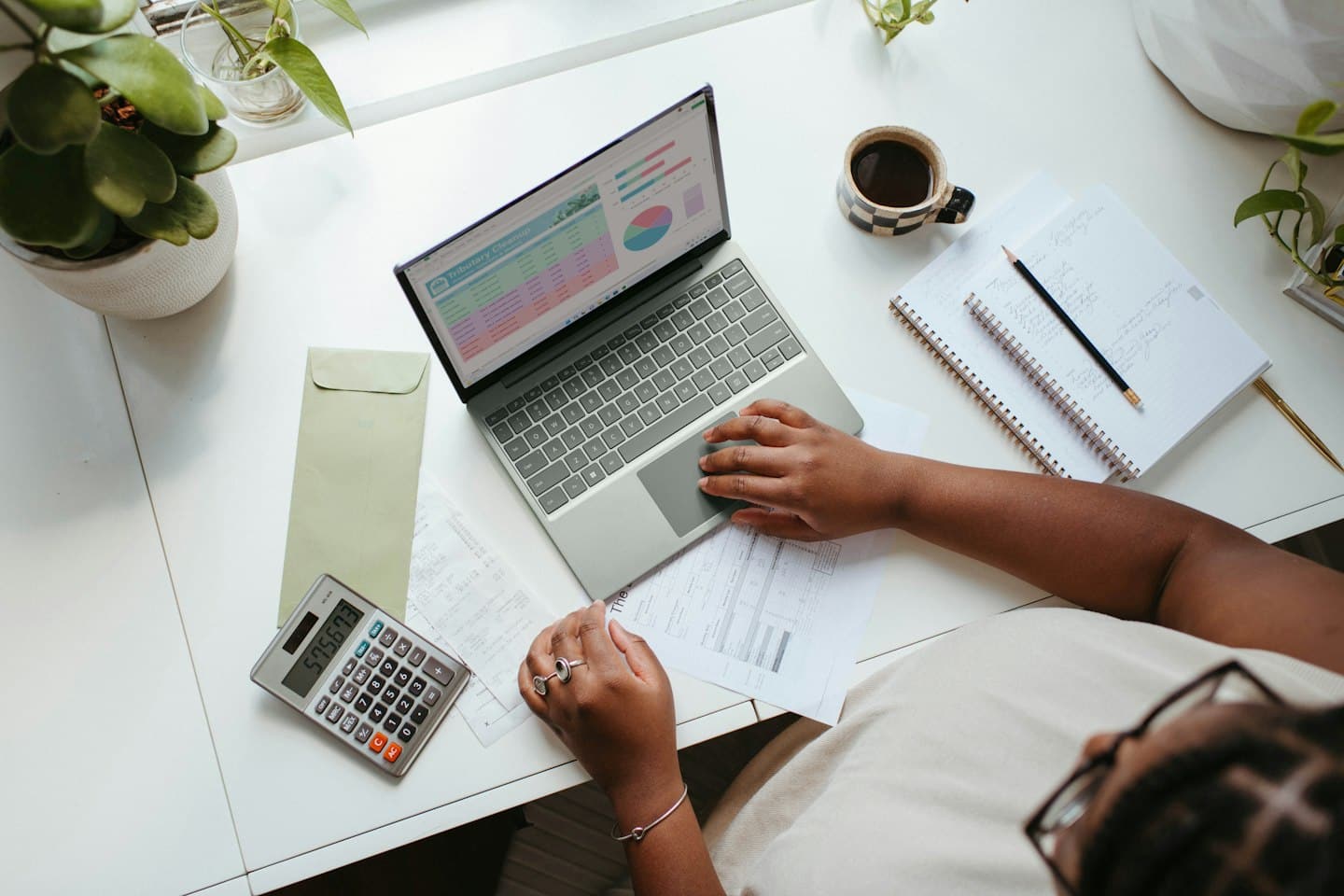 Professionnelle examinant des documents financiers avec une calculatrice et un ordinateur portable.