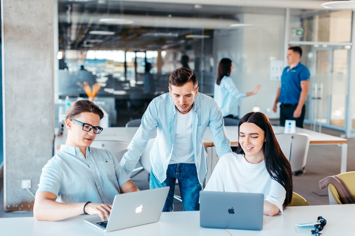 Équipe réunie autour d’ordinateurs portables dans un bureau.