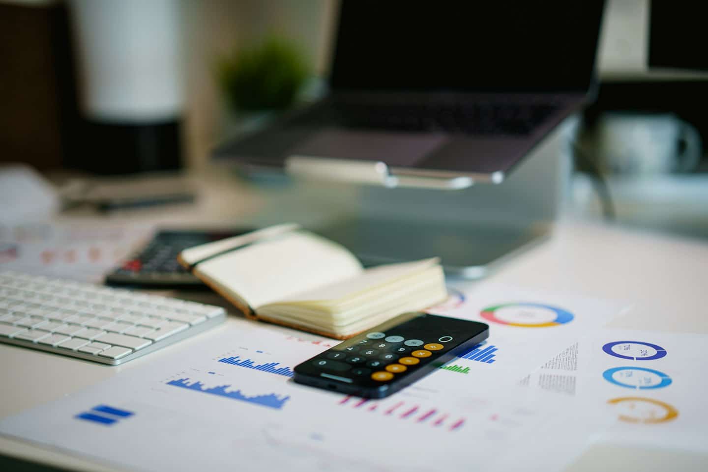 Calculatrice, graphiques et documents de suivi des dépenses sur un bureau.